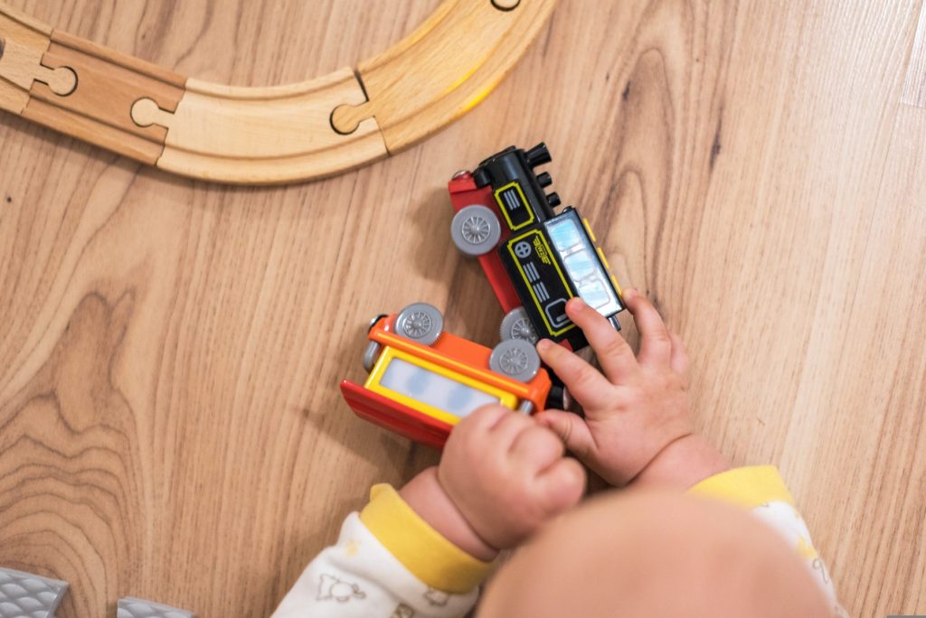 Enfant qui joue avec un train sur un parquet